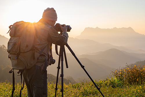 Fotograf v přírodě fotící na stativu